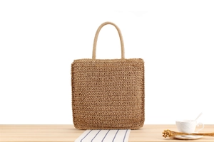 Close-up of bohemian woven bag with herringbone texture on a rustic wooden table