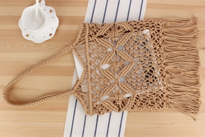 Close-up of bohemian hand-woven tote bag with geometric diamond patterns and long tassels