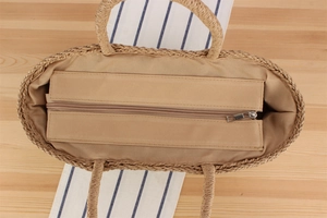 Detail view of woven straw tote bag featuring interior fabric lining and secure metal zipper