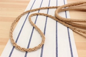 Detail of the brown hand-woven strap made from natural fiber on a rustic table