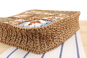 Detail of bohemian hand-woven bag featuring colorful crochet granny square patterns