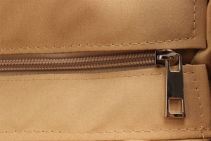 Detailed close-up of smooth nylon zipper and metallic slider on a woven crossbody bag