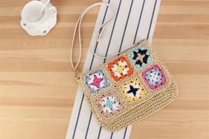 Detail of bohemian straw bag with colorful crochet granny squares on a wooden table