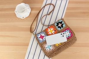 Detailed view of bohemian crochet flower bag size with a smartphone for scale