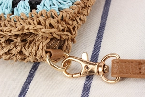 Dettaglio macro della borsa intrecciata con finiture in pelle e chiusura in metallo oro