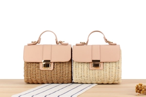 Détails de sacs en paille tressée avec bordure en cuir rose et fermoirs dorés sur table