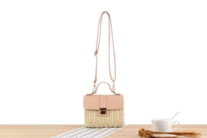 Détail du sac à bandoulière en paille tressée et cuir rose avec boucle métallique
