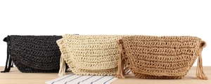 Flat lay of envelope woven straw clutch bags in black, beige, and tan with tassels