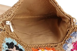 Dettaglio interno di borsa intrecciata con uncinetto floreale, fodera e zip dorata