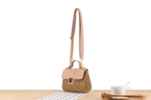 Détail de la texture en corde de papier tissée et du rabat en cuir rose sur un sac tressé
