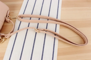 Détail d'une bandoulière réglable en cuir PU rose pâle avec mousquetons dorés brillants