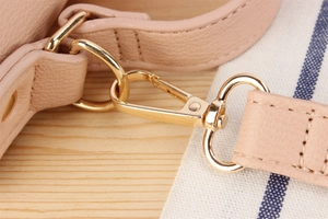Gros plan du crochet doré et de l'anneau en D sur le sac en cuir grainé rose