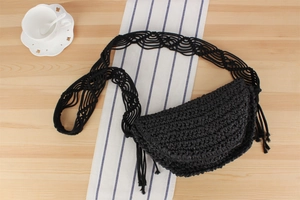 Detail of black woven crescent bag with straw texture and tassel shoulder strap decoration