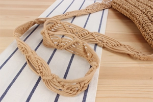 Detail view of the intricate hand-woven hollow pattern on a beige straw crossbody bag