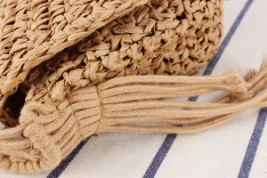Close-up of natural woven paper straw bag detail with thick cotton tassel fringe accent