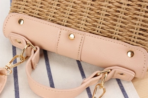 Détail d'un sac tissé en corde de papier avec bordure en cuir rose et rivets dorés