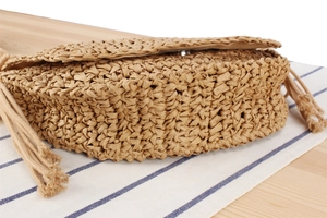 Close-up of woven straw bag texture with metallic magnetic buckle and fringe detail
