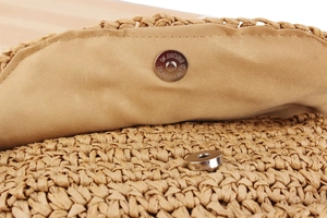 Detail of magnetic metal clasp closure on a woven straw crossbody bag with fabric lining