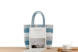 Dettaglio di una borsa tote intrecciata blu e grigia su tavolo in legno con decorazioni