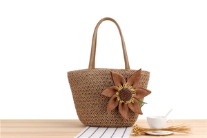 Dettaglio della borsa tote in paglia intrecciata a mano con girasole e manico in pelle marrone