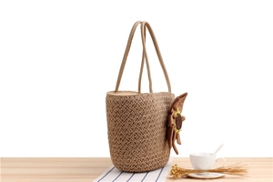 Dettaglio di borsa tote in paglia intrecciata con una grande decorazione a girasole giallo