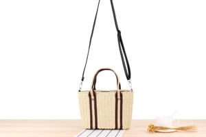 Detailed view of natural straw weave texture and brown fabric straps on a large tote bag