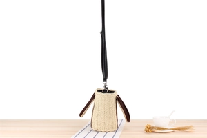 Detailed shot of beige woven straw bucket bag with contrasting brown leather handles