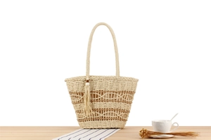 Detail of hand-woven tote bag with brown hollow patterns and a stylish fringe pendant