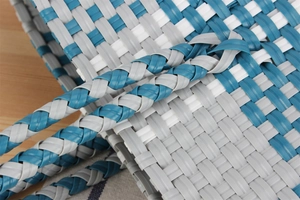 Dettaglio della borsa intrecciata blu e bianca con manici rinforzati e trama in plastica resistente