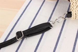 Detail of adjustable black leather strap with silver metal buckles on a woven bag