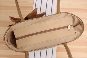 Dettaglio della capiente borsa shopper in paglia intrecciata con cerniera in metallo e fodera