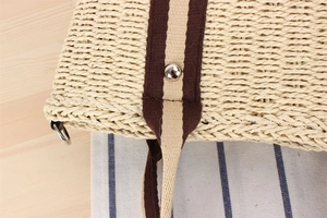 Detailed close-up of woven paper tote bag texture with striped webbing and metal rivets