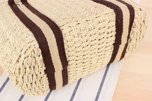 Close-up of woven straw handbag featuring cotton webbing and silver metal rivet details