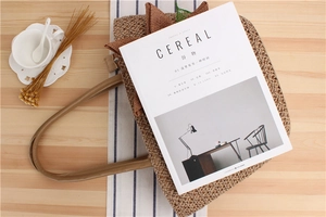 Dettaglio borsa tote intrecciata con manici in pelle su un tavolo in stile rustico