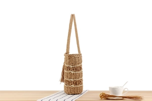 Detail of woven straw tote bag featuring bohemian fringe and wavy texture patterns