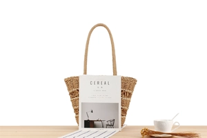 Close-up of a woven straw tote bag with rope handles on a light wooden table