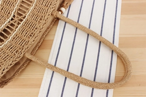Detail of woven straw bag with white bead accents, fringe tassels and inner lining
