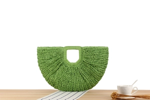 Detail view of a bright green crescent hand-woven bag with a square cut-out handle