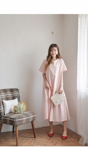 Detail of a minimalist light pink loose dress paired with a woven tassel clutch bag