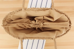 Detail of handwoven straw bag featuring internal fabric lining and drawstring closure