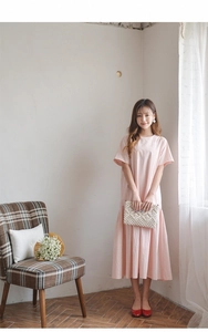 Detail of pink cotton-linen dress paired with a white handmade woven tassel clutch bag