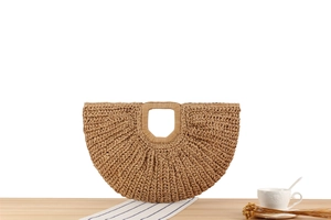 Detail of hand-woven straw texture and integrated circular handle on crescent handbag