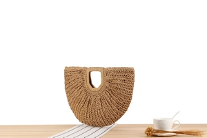 Detail of a handmade bohemian straw handbag with radial woven texture on a summer table