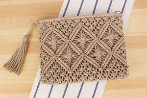Detail of bohemian cotton woven clutch bag featuring macrame diamond pattern and long tassel