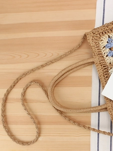 Bohemian hand-woven crossbody bag with blue and white crochet patterns on a raffia texture