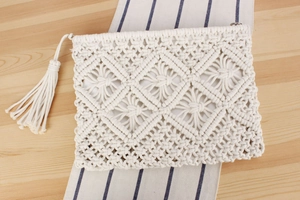 Detailed macro view of white macrame clutch with geometric diamond weave and fringe