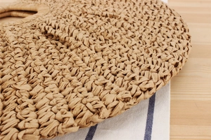Close-up of the intricate hand-woven texture and circular handle of a bohemian straw bag