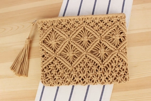 Detail of macramé woven beach clutch with tassel accents and geometric diamond pattern