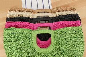 Detail shot of five woven summer handbags in green, pink, black, white, and tan colors