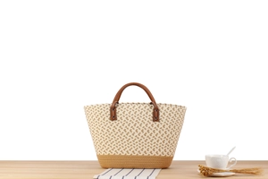Detail of bohemian hand-woven tote bag with brown leather handles on a wooden table